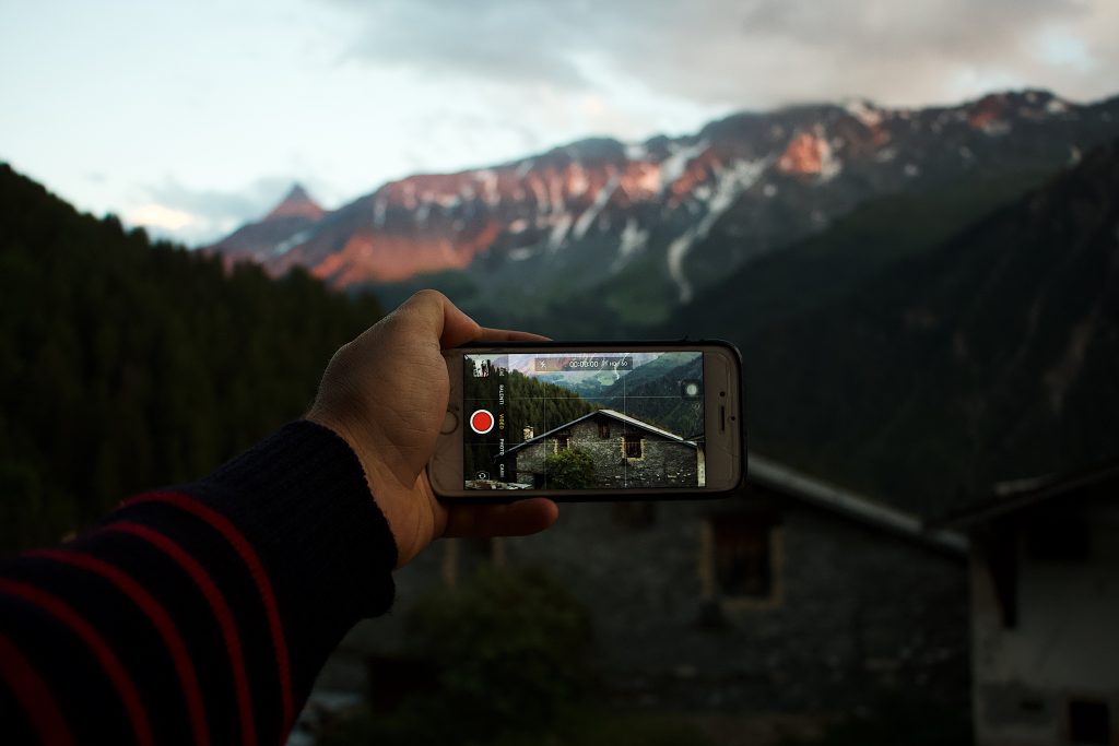 Um cara filmando uma montanha usando seu smartphone