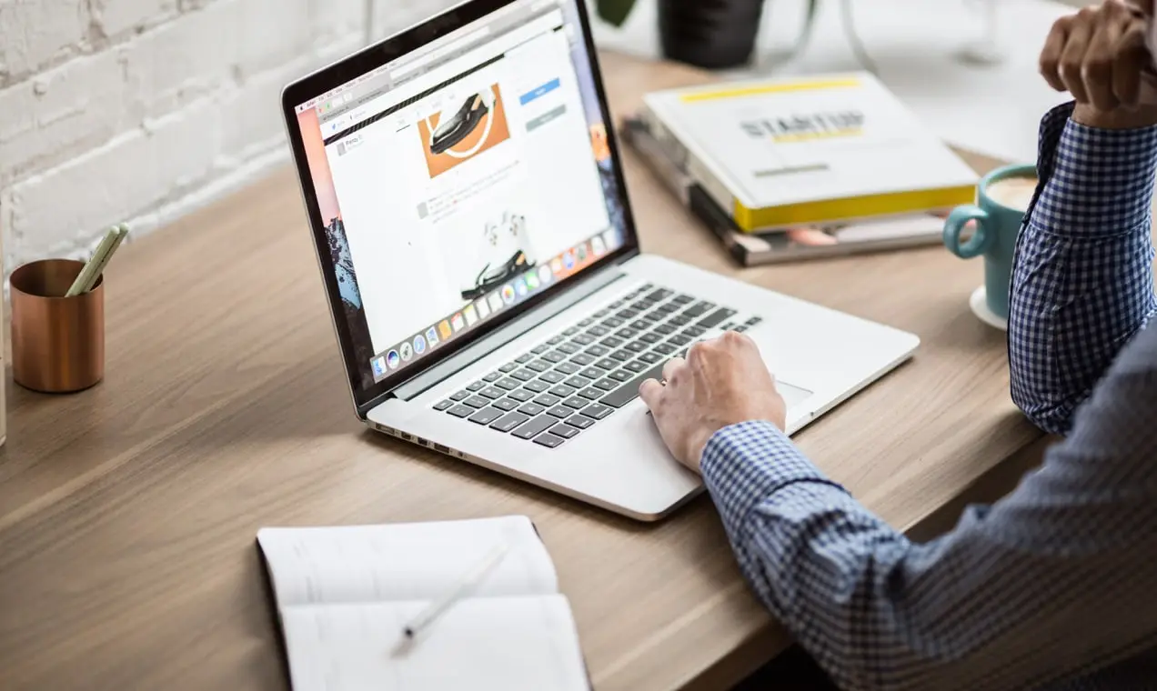 homme utilisant un ordinateur portable à un bureau en bois