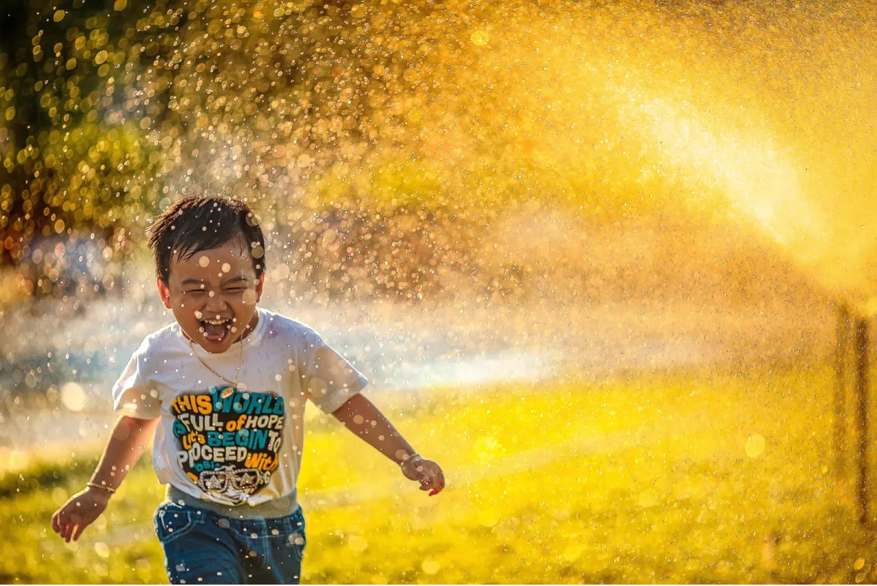 笑って水の中を走っている子供、カメラを見ている顔