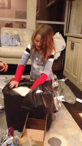 Gif con dos niños emocionados desempacando un regalo