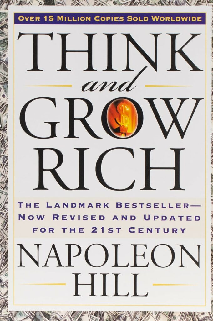 Cover des Buches Think and Grow Rich von Napoleon Hill mit dem Titel in großen schwarzen Buchstaben und Bildern von Dollarscheinen im Hintergrund.