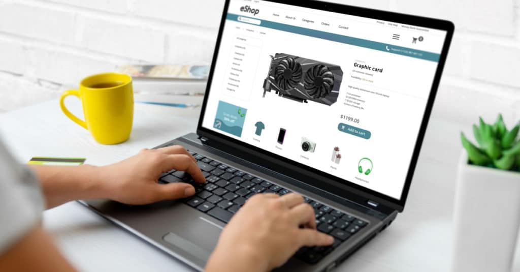 Eine Frau durchsucht einen Online-Shop namens eShop auf einem Laptop, der neben einer gelben Kaffeetasse steht