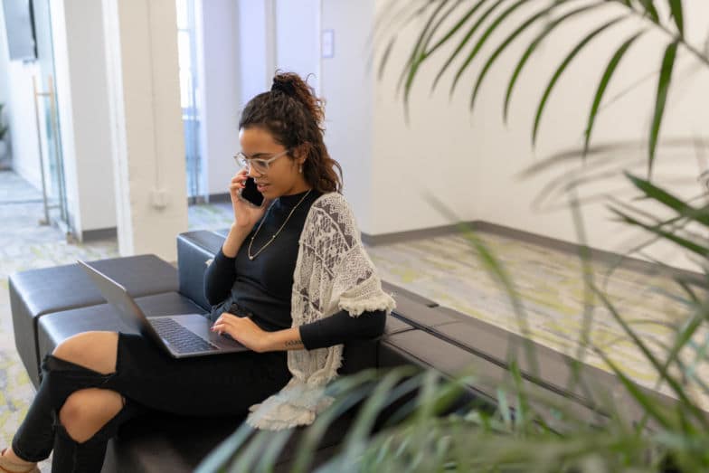kobieta rozmawia przez telefon o projekcie podczas pracy na laptopie