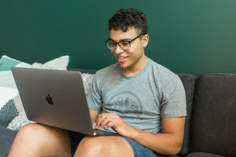 Homem trabalha no computador em um sofá.