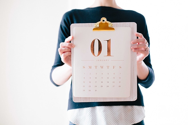 mulher segurando calendário folheado a ouro na área de transferência