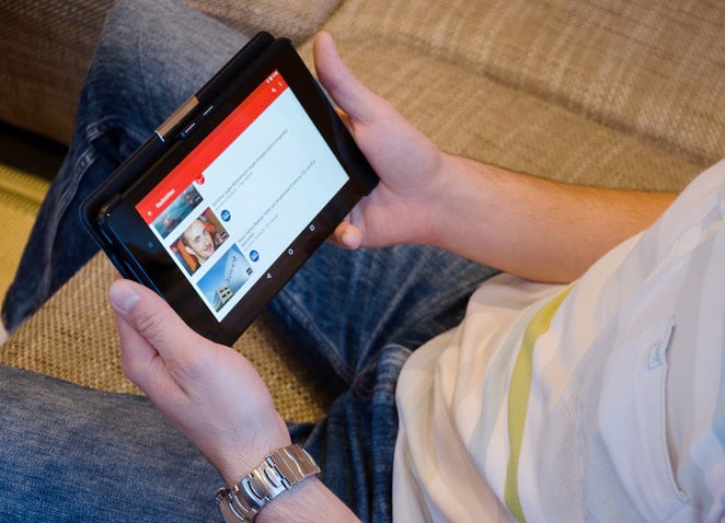 YouTube 閲覧ページでタブレットを使用してソファに座る男性