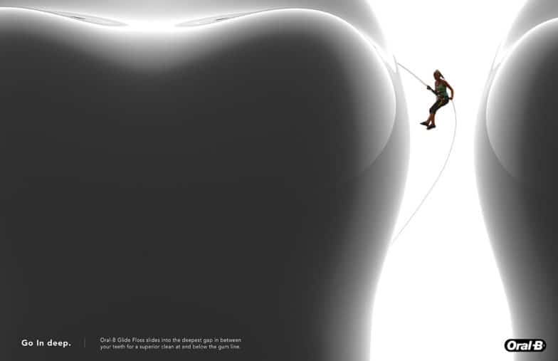 受賞歴のある「Go In Deep」キャンペーンの画像。クライミング ギアを身に着けた女性が巨大な歯の側面を下ります。