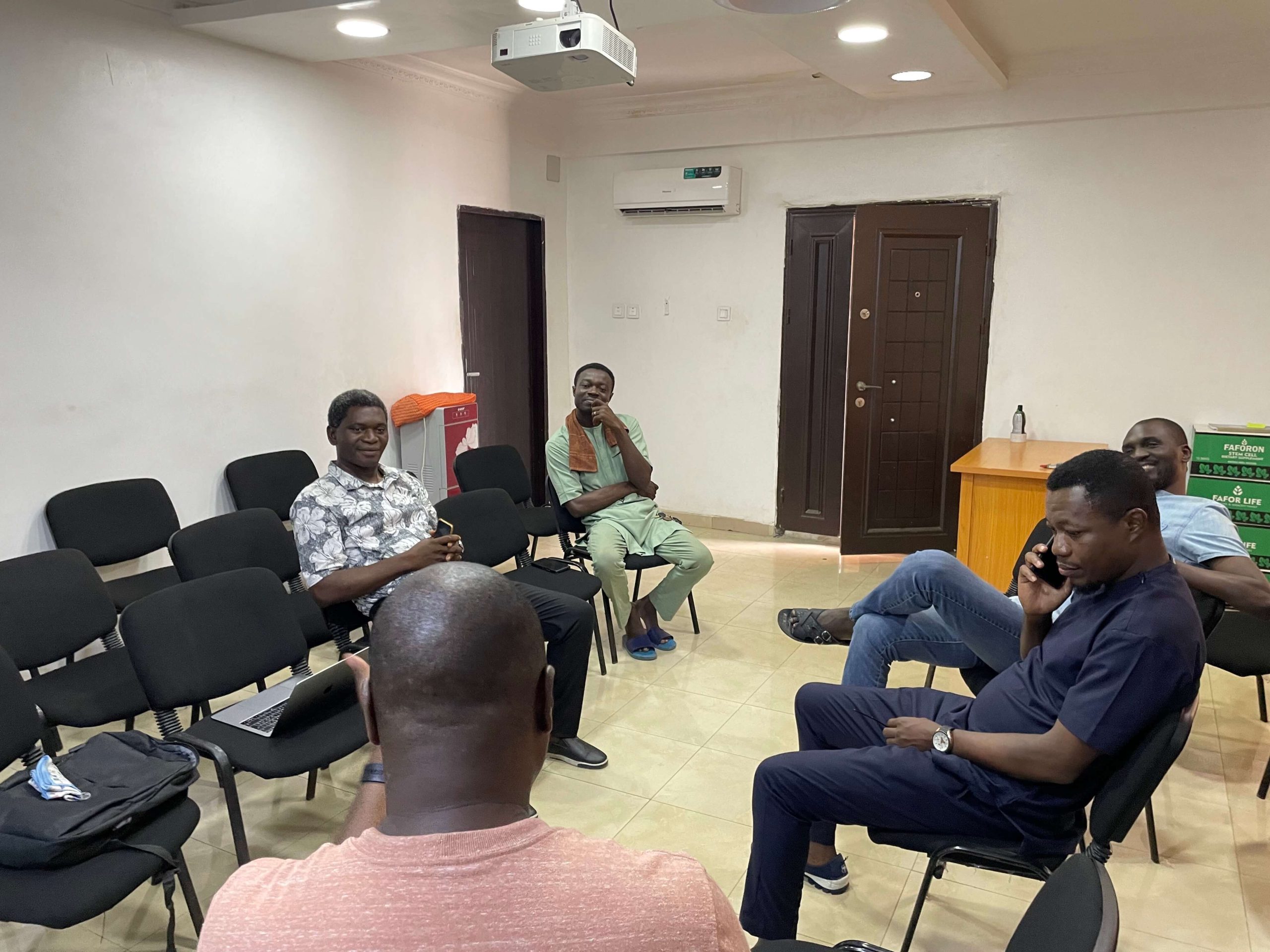 grupo de nigerianos sentados en círculo discutiendo Divi