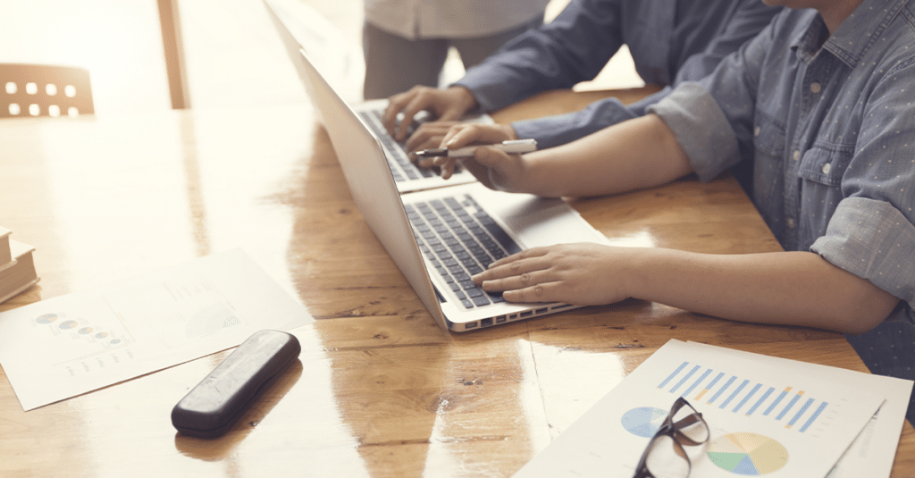 Zwei Personen arbeiten nebeneinander an Laptops.