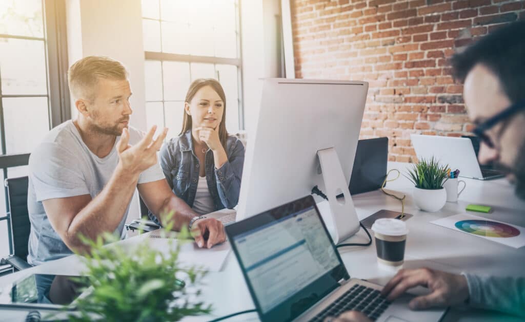 Menschen, die in einem Büro an verschiedenen Computerbildschirmen arbeiten