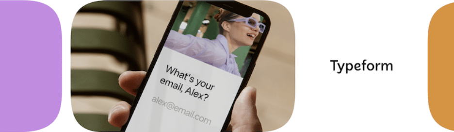 Close de uma mão segurando um smartphone exibindo uma pergunta interativa "Qual é o seu e-mail, Alex?" com uma figura desfocada ao fundo usando óculos de laboratório, ao lado do logotipo Typeform, enfatizando uma experiência personalizada do usuário em formulários online.