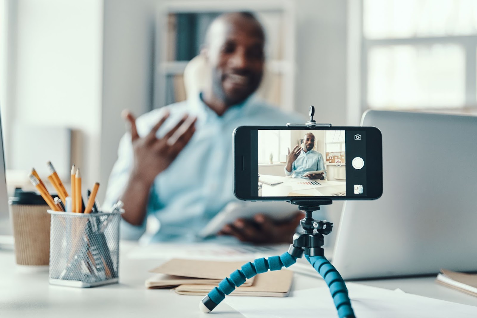 Un uomo registra un video su un iPhone in cui si trova in un ufficio ben illuminato.