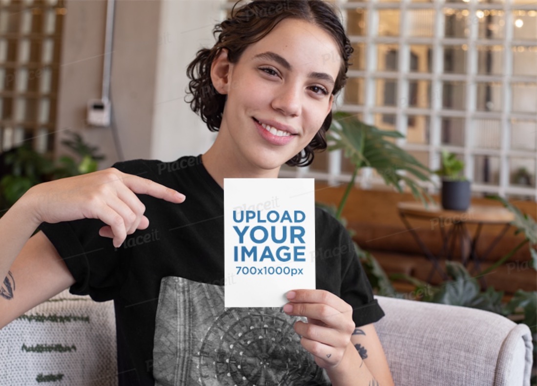 femme souriante pointant sur une maquette de carte postale a6